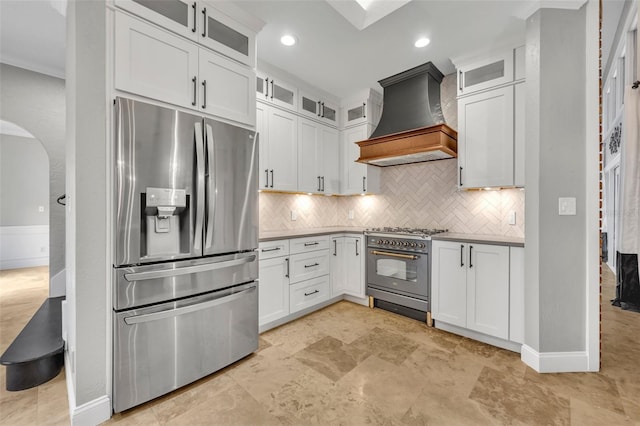 kitchen featuring tasteful backsplash, white cabinets, stainless steel appliances, and custom range hood