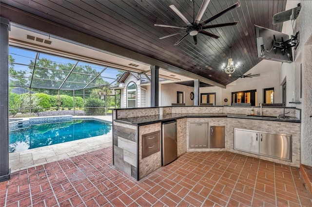 view of swimming pool featuring an outdoor kitchen, a lanai, ceiling fan, sink, and a patio