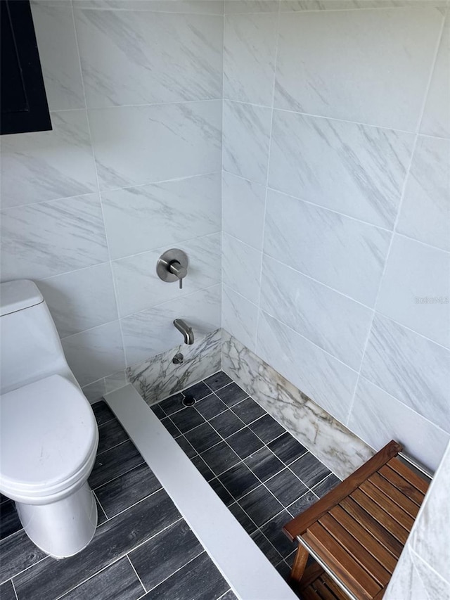 bathroom featuring a tile shower, tile walls, and toilet