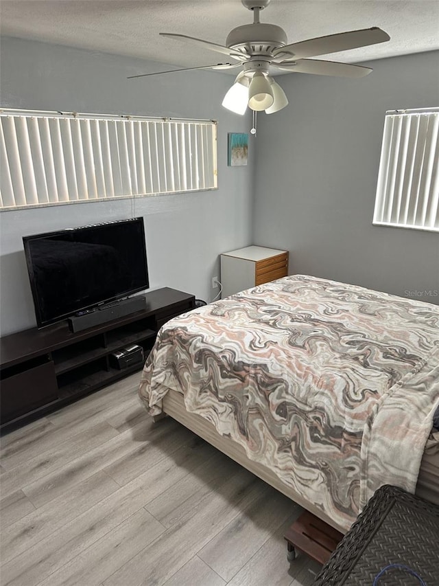 bedroom featuring ceiling fan, a textured ceiling, and light hardwood / wood-style floors