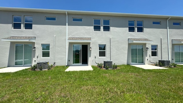 rear view of house with cooling unit and a lawn