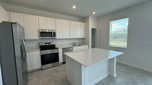 kitchen featuring white cabinets, stainless steel appliances, a kitchen island, and sink