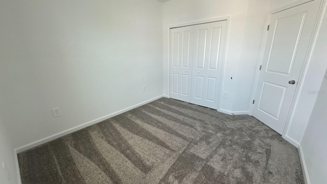 unfurnished bedroom featuring a closet and dark carpet