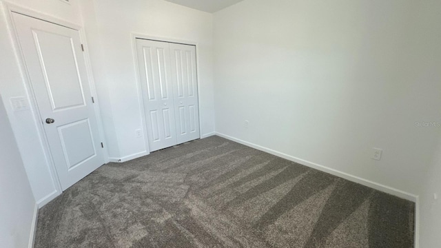 unfurnished bedroom with dark carpet and a closet