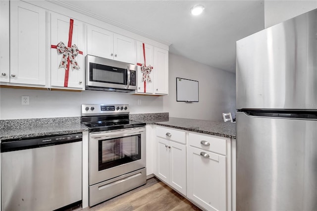 kitchen with appliances with stainless steel finishes, light wood-type flooring, white cabinetry, and dark stone counters