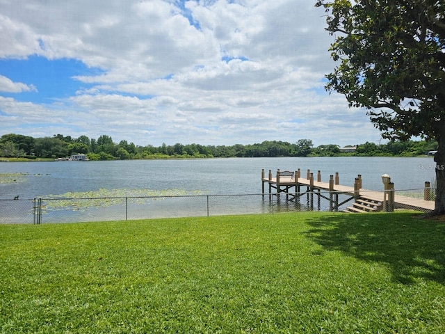 view of dock with a yard and a water view