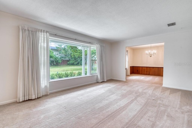 unfurnished room featuring crown molding, a textured ceiling, light carpet, and a chandelier