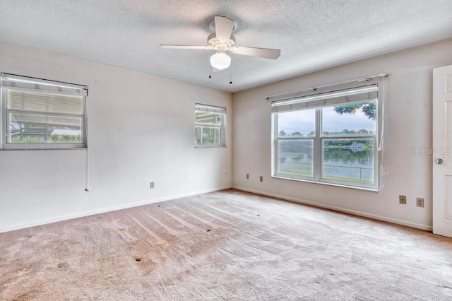 unfurnished room with light carpet, a textured ceiling, a water view, and ceiling fan