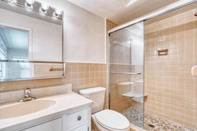 bathroom featuring an enclosed shower, vanity, toilet, and tile walls