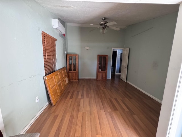 unfurnished living room featuring ceiling fan, a high ceiling, an AC wall unit, wood-type flooring, and a textured ceiling