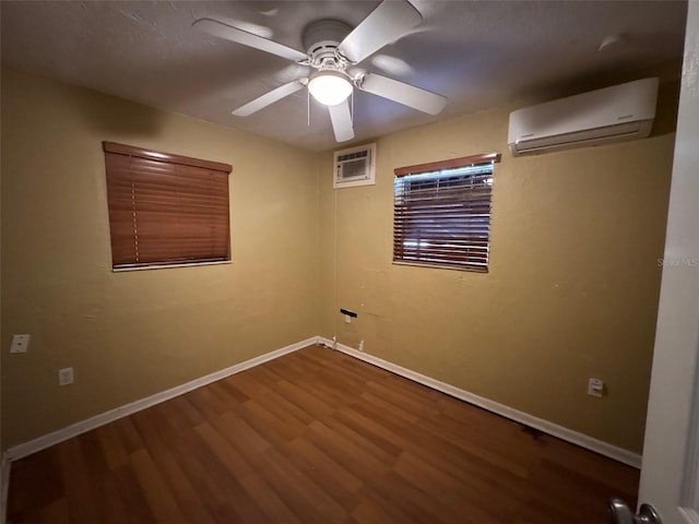 unfurnished room with ceiling fan, wood-type flooring, and a wall mounted air conditioner