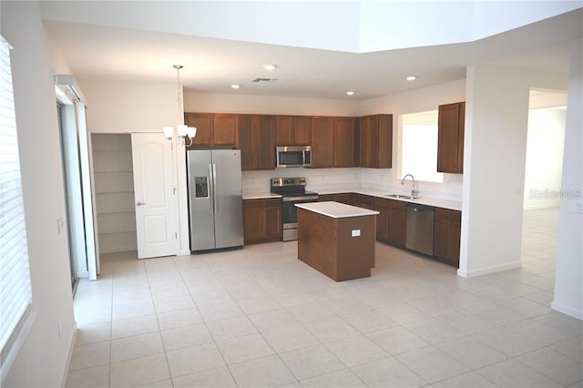 kitchen with a center island, sink, stainless steel appliances, pendant lighting, and light tile patterned floors