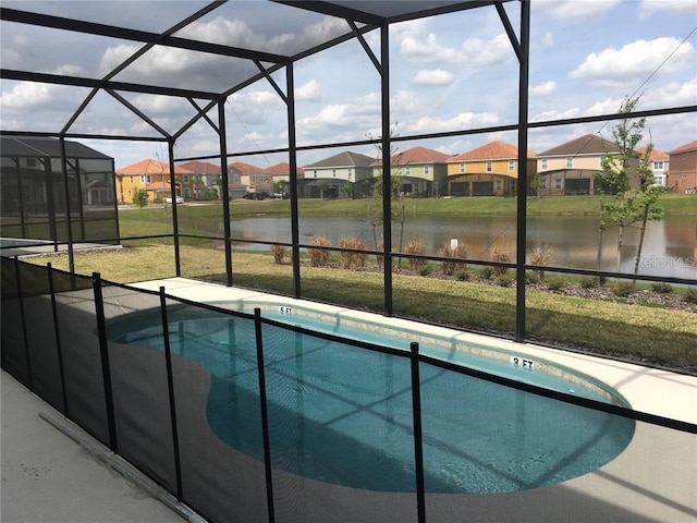 view of swimming pool featuring a lawn, glass enclosure, a water view, and a patio