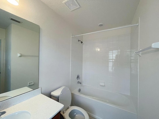 full bathroom with vanity, tiled shower / bath, a textured ceiling, and toilet