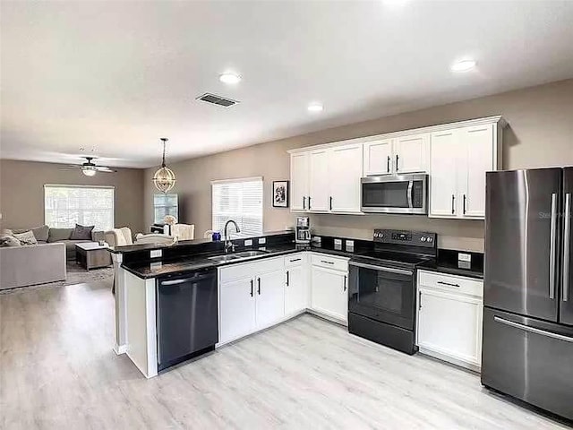 kitchen featuring kitchen peninsula, decorative light fixtures, white cabinets, and black appliances