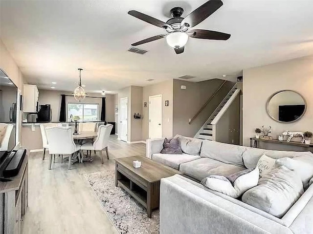 living room featuring light hardwood / wood-style flooring and ceiling fan with notable chandelier