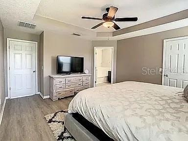 bedroom featuring hardwood / wood-style flooring, ceiling fan, and a raised ceiling