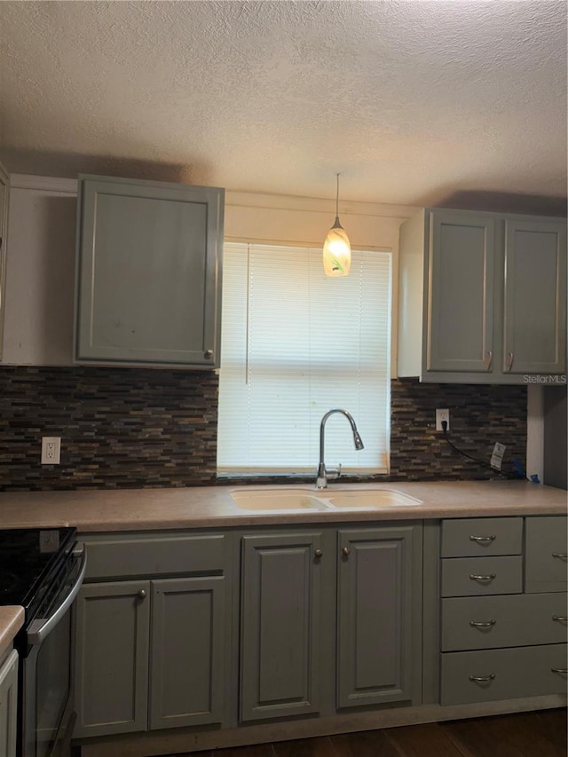 kitchen with backsplash, sink, hanging light fixtures, stainless steel range with electric cooktop, and gray cabinetry