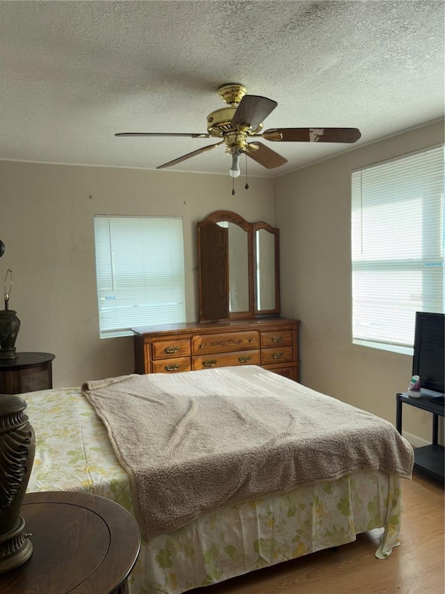 bedroom featuring a textured ceiling, ceiling fan, and light wood-type flooring