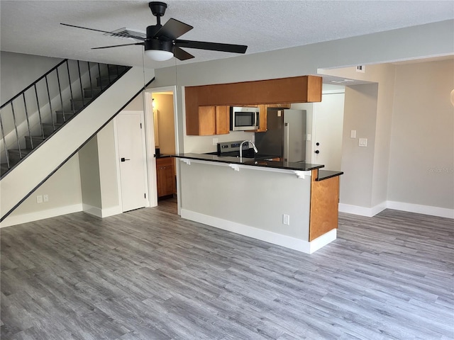 kitchen featuring a textured ceiling, stainless steel appliances, ceiling fan, sink, and wood-type flooring