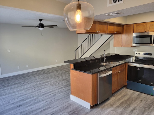 kitchen with kitchen peninsula, stainless steel appliances, ceiling fan, sink, and hardwood / wood-style floors