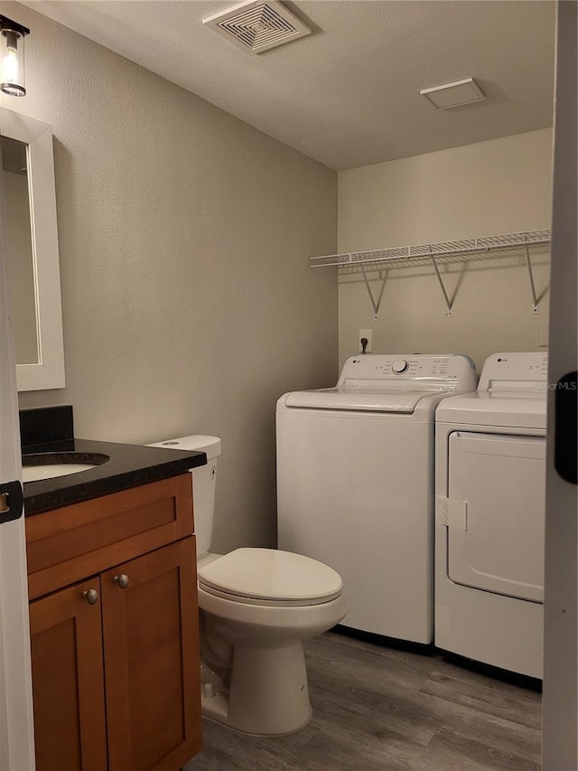 bathroom with a textured ceiling, vanity, separate washer and dryer, hardwood / wood-style flooring, and toilet