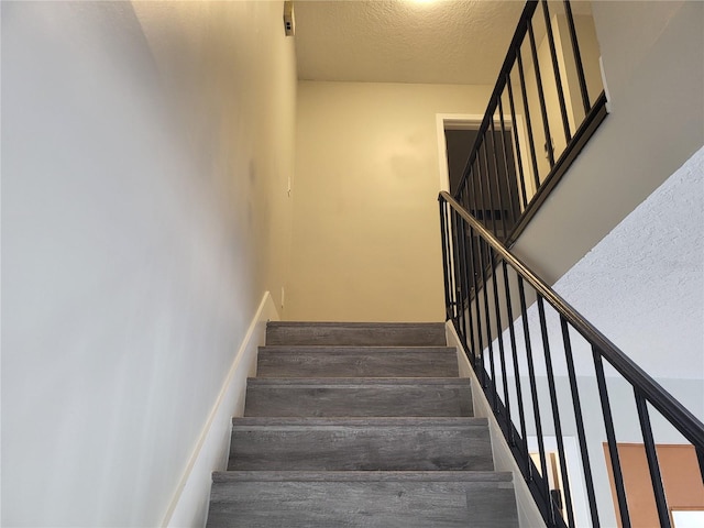 staircase featuring a textured ceiling