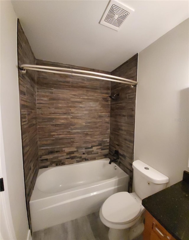 full bathroom featuring vanity, tiled shower / bath combo, and toilet