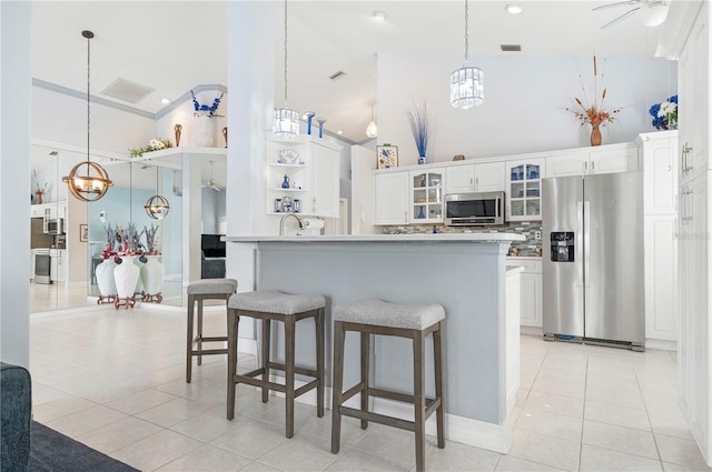 kitchen with a breakfast bar area, open shelves, light tile patterned floors, appliances with stainless steel finishes, and glass insert cabinets