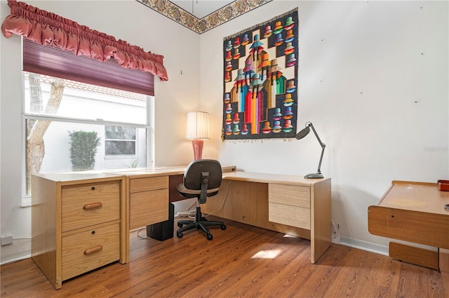 office area featuring light wood-style floors, built in desk, and baseboards