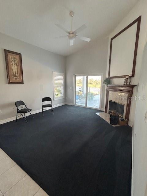 living area featuring baseboards, ceiling fan, tile patterned floors, vaulted ceiling, and a high end fireplace