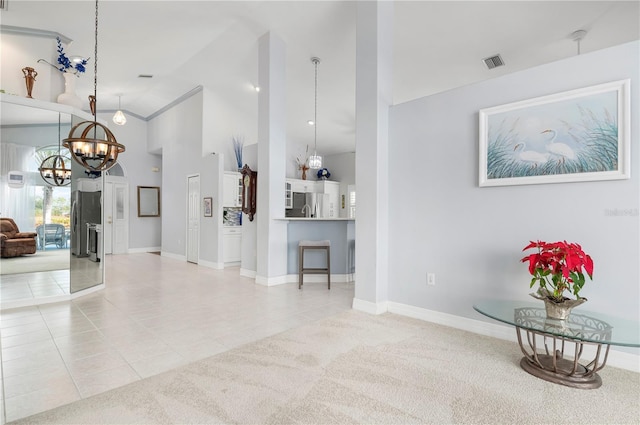 carpeted living area with visible vents, a chandelier, baseboards, tile patterned flooring, and high vaulted ceiling