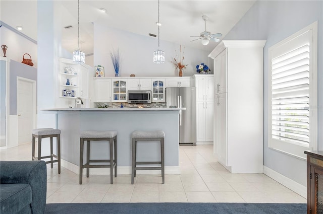 kitchen with glass insert cabinets, a breakfast bar area, stainless steel appliances, and light tile patterned flooring