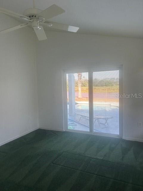 empty room with a ceiling fan, dark carpet, and baseboards