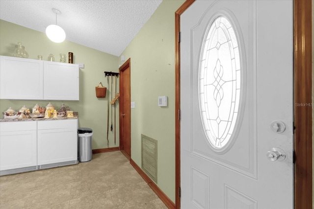 entryway featuring a healthy amount of sunlight, a textured ceiling, and vaulted ceiling