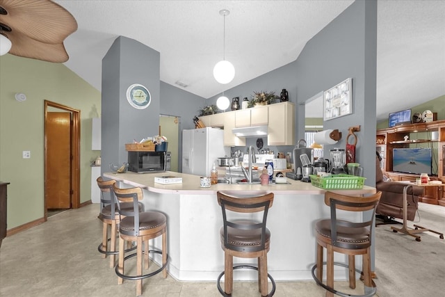 kitchen featuring white refrigerator with ice dispenser, sink, vaulted ceiling, a kitchen bar, and kitchen peninsula