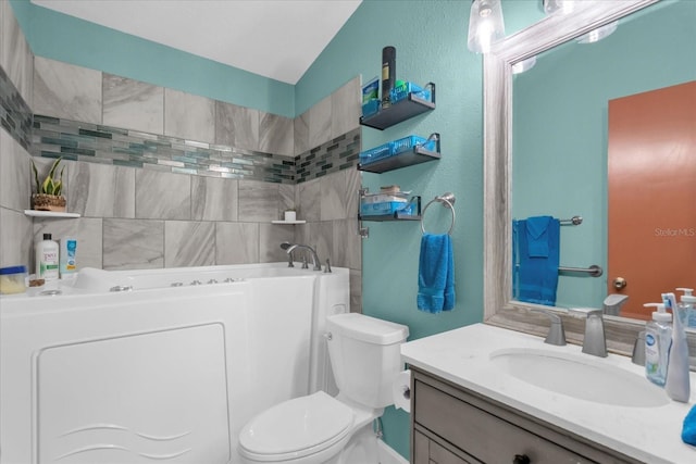 bathroom featuring washer / dryer, vanity, toilet, and a tub