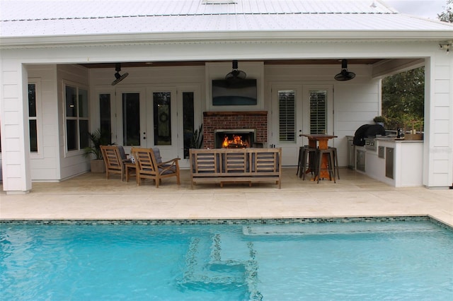 view of swimming pool featuring an outdoor living space with a fireplace, area for grilling, ceiling fan, and a patio area