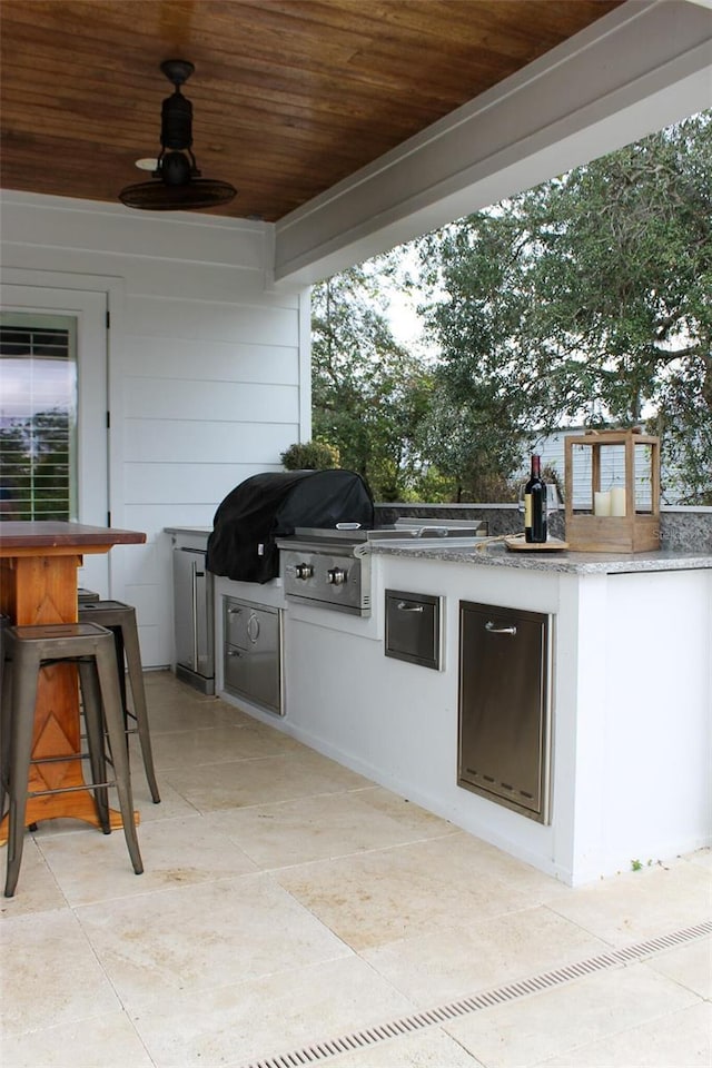 view of patio / terrace with grilling area, ceiling fan, a bar, and an outdoor kitchen