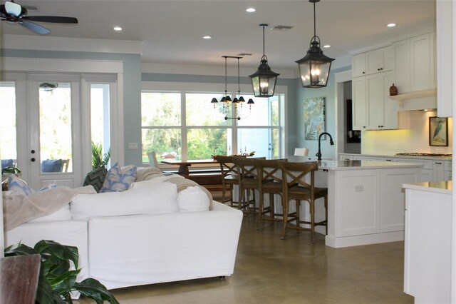 living room featuring ceiling fan with notable chandelier and sink