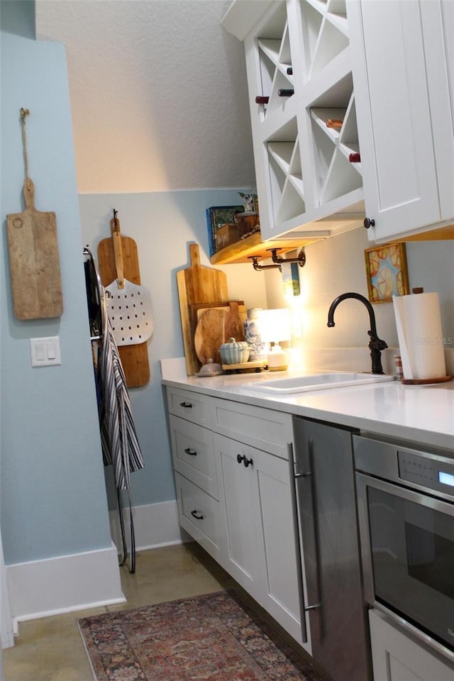 kitchen featuring oven, white cabinetry, and sink