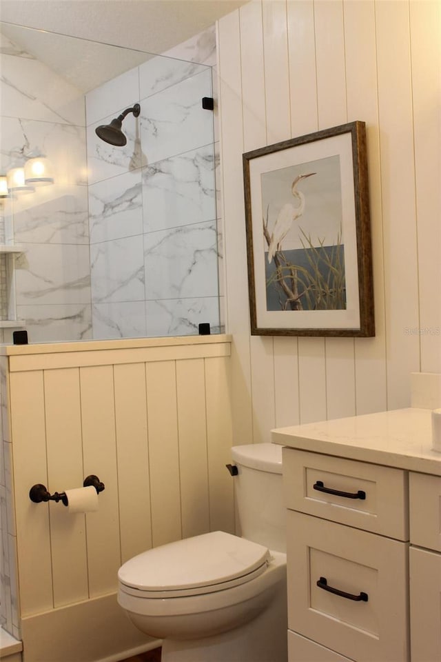 bathroom featuring toilet, vanity, and tiled shower