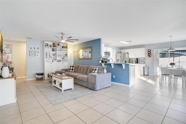 living room with ceiling fan, sink, light tile patterned floors, and a textured ceiling