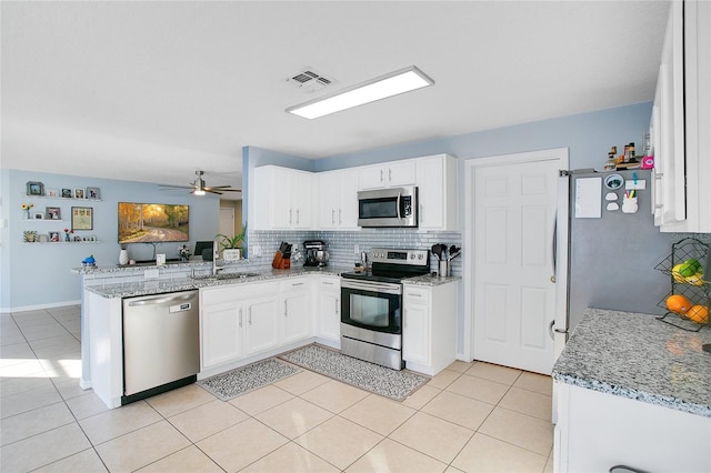 kitchen with white cabinetry, sink, stainless steel appliances, light stone counters, and kitchen peninsula