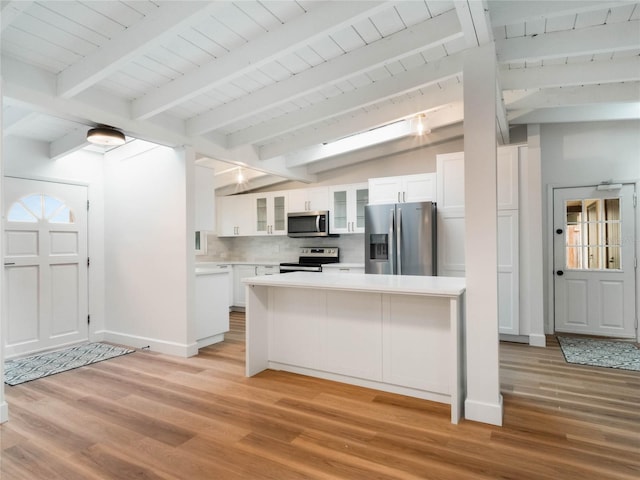 kitchen featuring white cabinets, vaulted ceiling with beams, light hardwood / wood-style floors, and stainless steel appliances