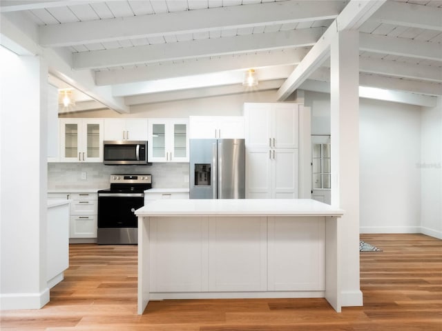 kitchen featuring backsplash, stainless steel appliances, vaulted ceiling with beams, light hardwood / wood-style floors, and white cabinetry