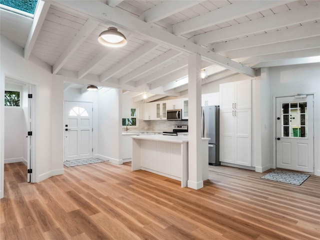 kitchen with white cabinets, decorative backsplash, vaulted ceiling with beams, light hardwood / wood-style floors, and stainless steel appliances