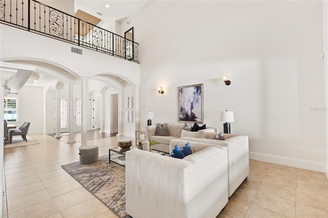 tiled living room with ornate columns and a high ceiling