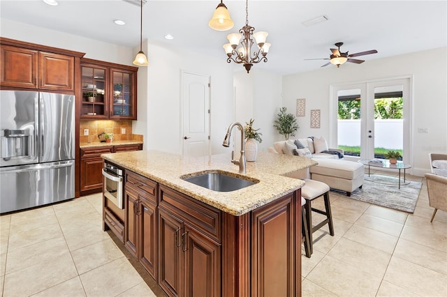 kitchen featuring appliances with stainless steel finishes, french doors, ceiling fan with notable chandelier, sink, and decorative light fixtures