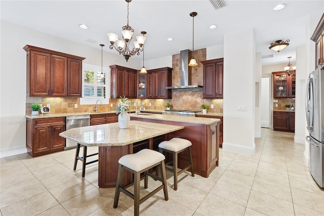 kitchen featuring a breakfast bar area, a center island, wall chimney exhaust hood, and appliances with stainless steel finishes